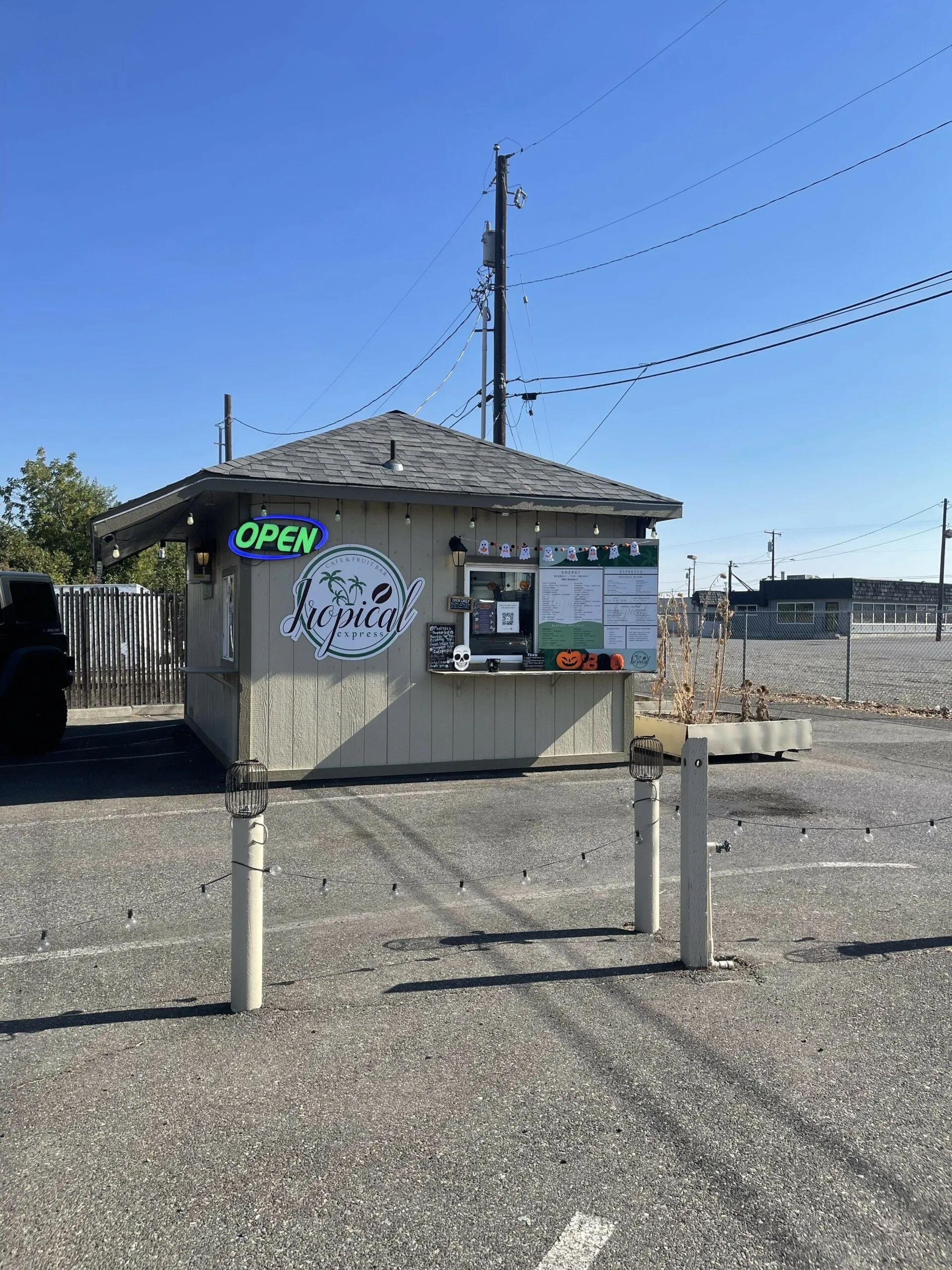 The Tropical Express drive-thru stand with a lit OPEN sign against a clear blue sky